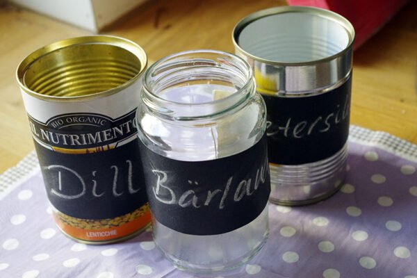 Recycled tin cans, and glass from conserves, to be reused as pots for herb seedlings.